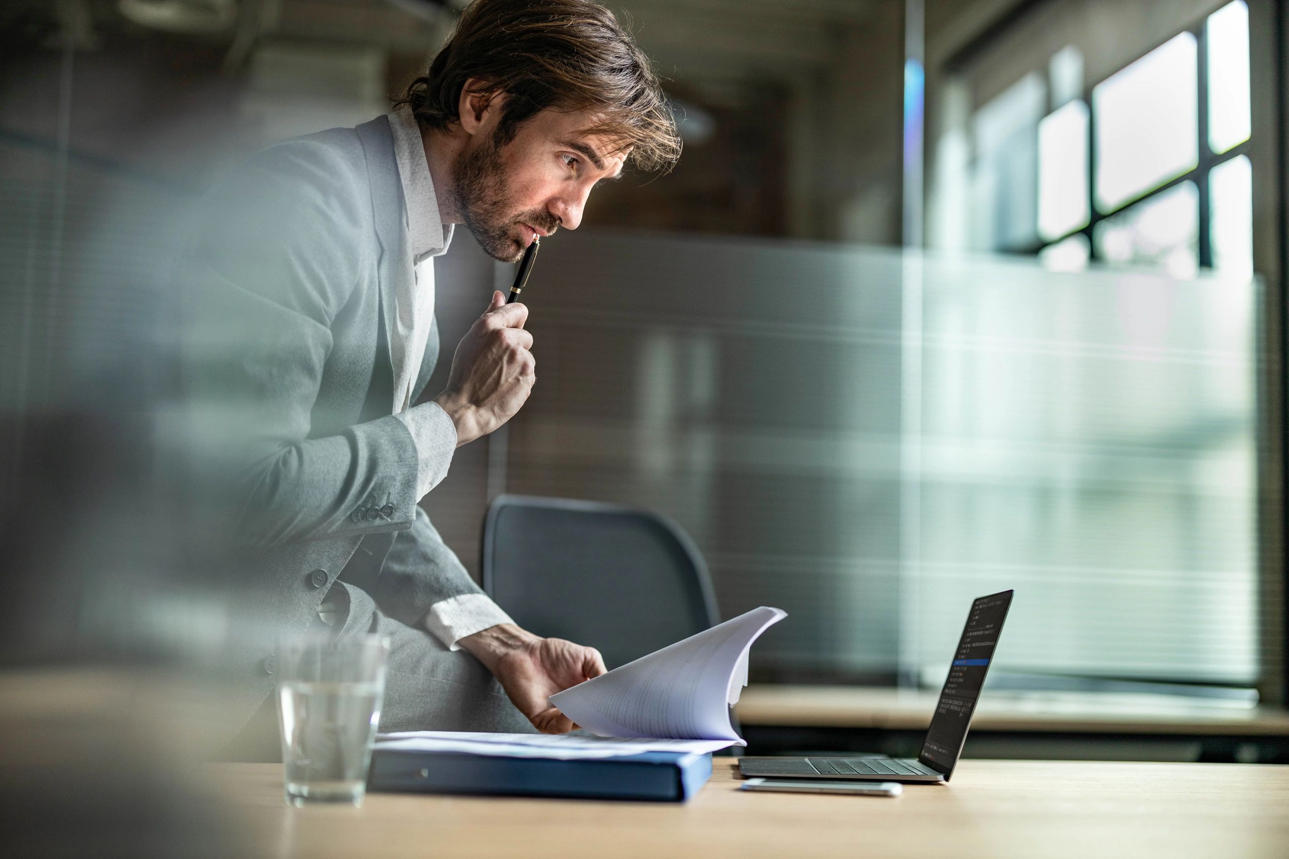 Analyst reviewing documents and data on a laptop