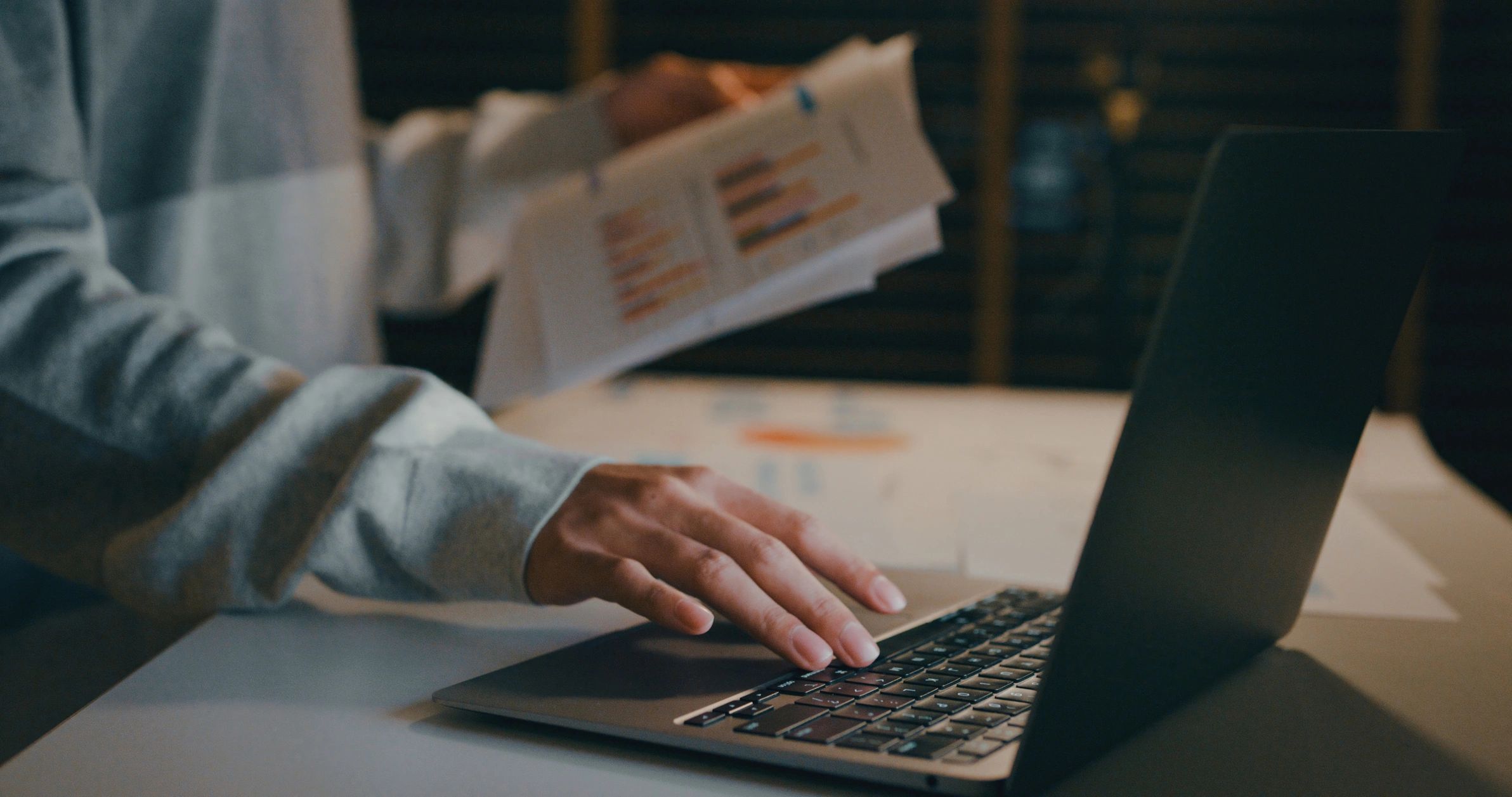 Professional reviewing documents and data on a laptop